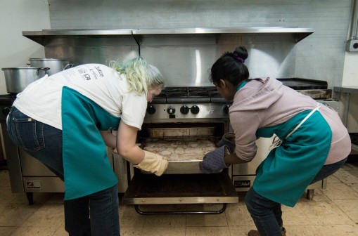 Ball State Senior Landscape Architecture major Virginia Jenkins(left) and (right) Urban Planning Graduate Student Varu Musumuri, pulls out a large pan of chicken and potatoes to serve to the Avondale community for Thursday night commune dinner. Jenkins directed the team of students and volunteers as she provided all the recipes served at the dinner, ÒThey are just in my headÉ all from try and fail.Ó said Jenkins. Grace Hollars, DN