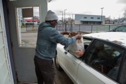 Pastor Simon Maina Mungai of Morning Star Church in Muncie, IN hands a sack of food items to the lady in the car on Saturday April 9, 2022. Some people that come by pick up food for other families, not just their own. This car was picking up for two families. Anna Sego, J437